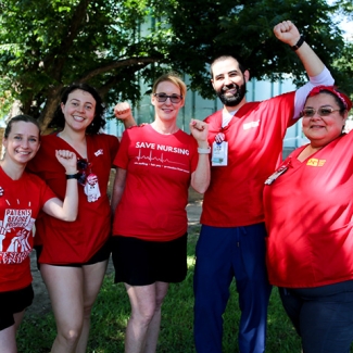 Five nurses standing next to each other smiling and with raised fists