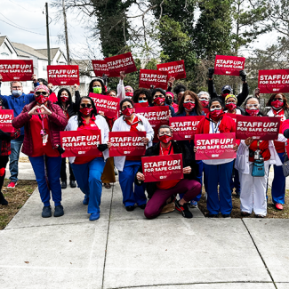 Group of Atlanta VA nurses holding signs "Staff up for safe care! End crisis care now!"