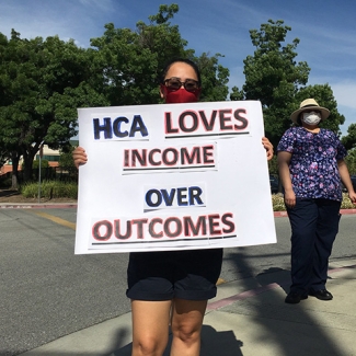 Nurse holds sign "HCA loves income over outcomes"