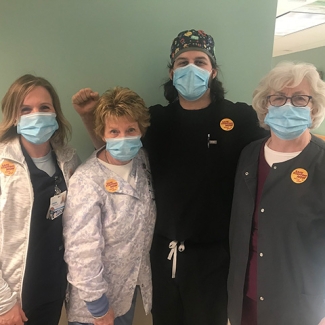 Group of four nurses inside hospital wearing stickers in support of safe staffing