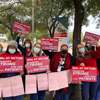Nurses outside hold signs "RNs at Seton standing strong for our patients"