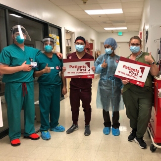 Group of nurses inside hospital hold signs "Patients First in the Hospital"