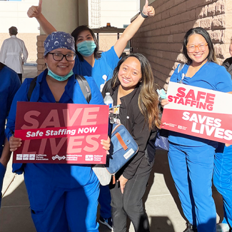 MountainView hospital nurses holding signs "Safe staffing. Save lives." and "Save lives. Safe staffing NOW."