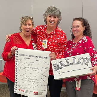 Three nurses smiling and holding ballot box