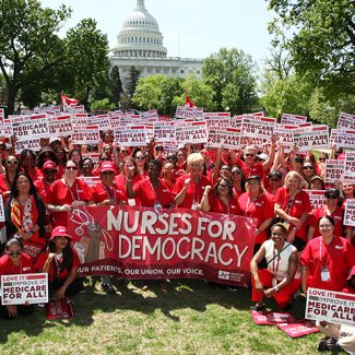 Large group of nurses in front of U.S. capitol with signs "Love it! Improve it! Medicare For All!"