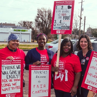 Four nurses outside holding signs "Nurses Deserve a Fair Contract" and other signs in support of UMC nurses and patients