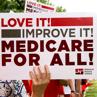 Holding sign in front of a Capitol building "Love it! Improve it! Medicare for all!"
