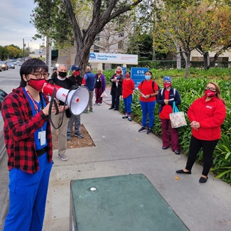 Nurses outside PIH Health Good Samaritan Hospital, one speaking through megaphone