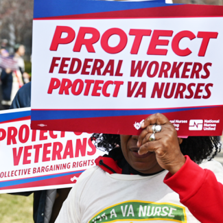 Nurse holding sign "Protect federal workers. Protect VA nurses" and "Protect Veterans. Collective Bargainiing Rights."