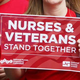 Nurse holds sign "Nurses & Veterans Stand Together"