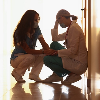 Two nurses kneeling in hospital hallway