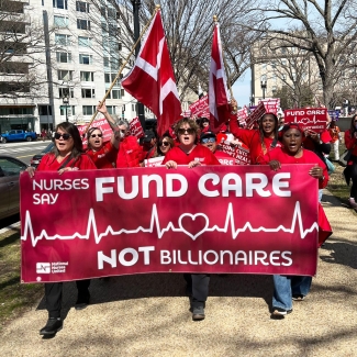 Nurses marching, holding banner "Fund Care NOT Billionaires"