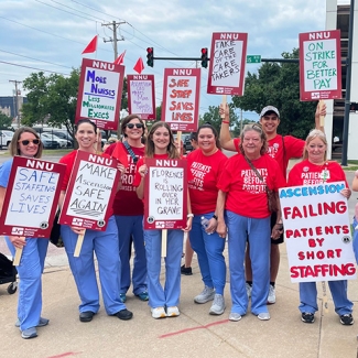 Large group of nurses outside hospitals holding various signs calling for nurse and patient safety