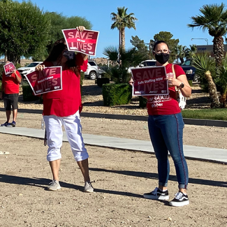 RNs holding signs, SAVE LIVES