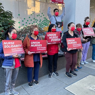 Group of nurses outside Chinese Hospital holding signs "Union Nurses Build Healthy Communities"