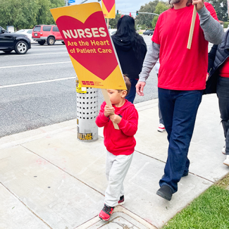 Child holding sign: "Nurses are the heart of patient care"