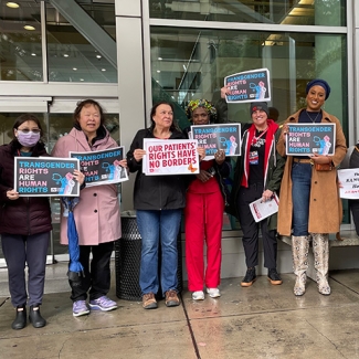 Group of nurses outside hospital holding signs "Transgender Rights are Human Rights"