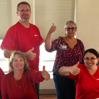 Group of nurses at table giving thumbs up