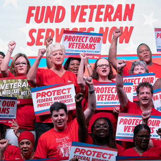 Group of nurses with raised fists holding signs supporting veterans and VA nurses