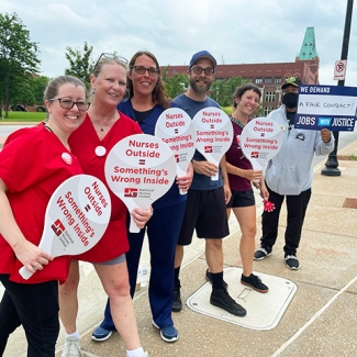 Group of nurses outside holding signs "Nurses Outside = Somethings Wrong Inside"