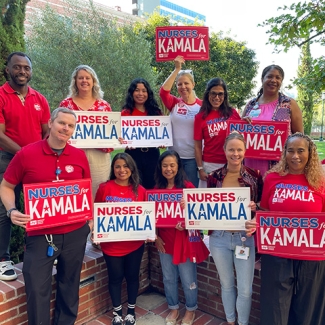 Group of nurses holding red and white "Nurses for Kamala" signs
