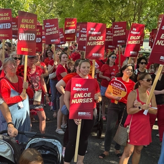 Large group of nurses outside holding signs "Enloe Nurses United"