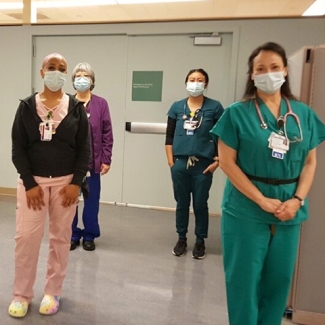 Group of four masked nurses inside hospital
