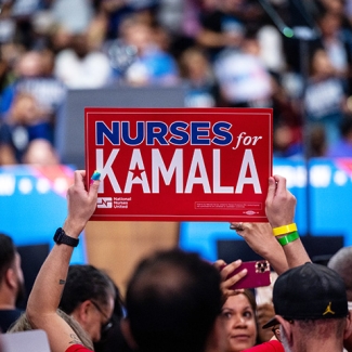 Arms holding sign "Nurses for Kamala"