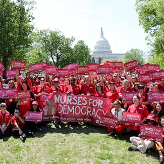 Group of nurses holding signs and banner "Nurses for Democracy"