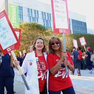 Nurses outside hospital holding signs "Nurses are the true spirit of charity"