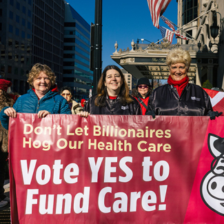 Four nurses outside holding banner "Vote YES to Fund Care"