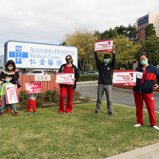 Nurses in front of Alhambra Hospital Medical Center sign hold signs calling for safe staffing and patient safety