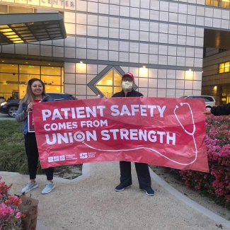 UCSD La Jolla nurses holding banner that reads "Patient safety comes from union strength!"