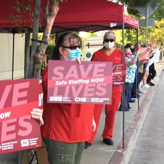 Nurses holds sign "Safe Staffing Now"