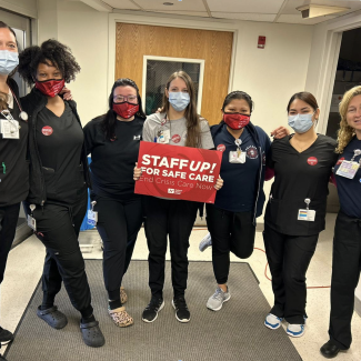 Nurses holding sign that reads "Staff up for safe care!"