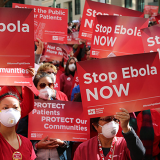 Nurses holding signs 'Stop Ebola NOW' and 'Protect Patients, Protect our Communities'