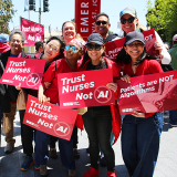 Group of nurses holding signs "Trust Nurses Not A.I." and "Patients are NOT algorithms"
