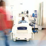 Child in hospital bed being passed by hospital staff