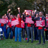 Group of nurses outside, holding lights and signs "Nurses Demand Justice for Patients and Workers Everywhere" and "Count Every Vote"