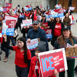 Nurses marching holding signs "ICE Not Welcome Here"