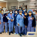 Group of nurses standing side-by-side, in hospital, smiling