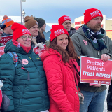 Group of nurses outside, in cold weather clothibg, wearing MSNA beanies, holding signs "Protect Patients, Trust Nurses"