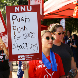 Nurse on picket line holds sign "Push Push for Safe Staffing"