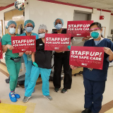 Large groups of nurses inside hospital hold signs "Staff Up for Safe Care"