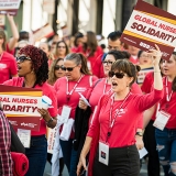 Nurses marching, holding signs "Global Nurses Solidarity"