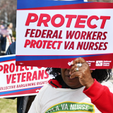 Nurse holding sign "Protect federal workers. Protect VA nurses" and "Protect Veterans. Collective Bargainiing Rights."