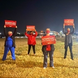 Group of nurses outside hold signs "Staff Up for Safe Care"