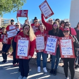 Large group of nurses outside MountainView hospital holding signs "Put Patients Over Profits"