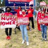 Nurses and community outside Cook County ER with signs "Safe Staffing Saves Lives" and "Nurse Power"