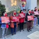 Group of nurses outside Chinese Hospital holding signs "Union Nurses Build Healthy Communities"